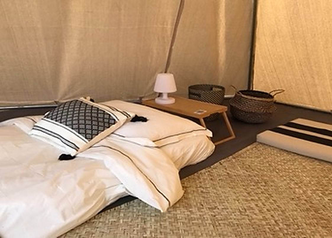 A dressed double bed inside a teepee