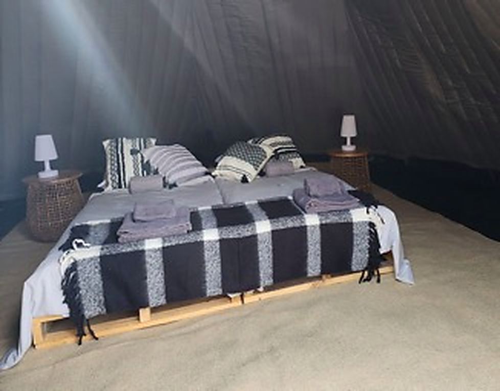Interior of a teepee dressed with beds and soft lighting