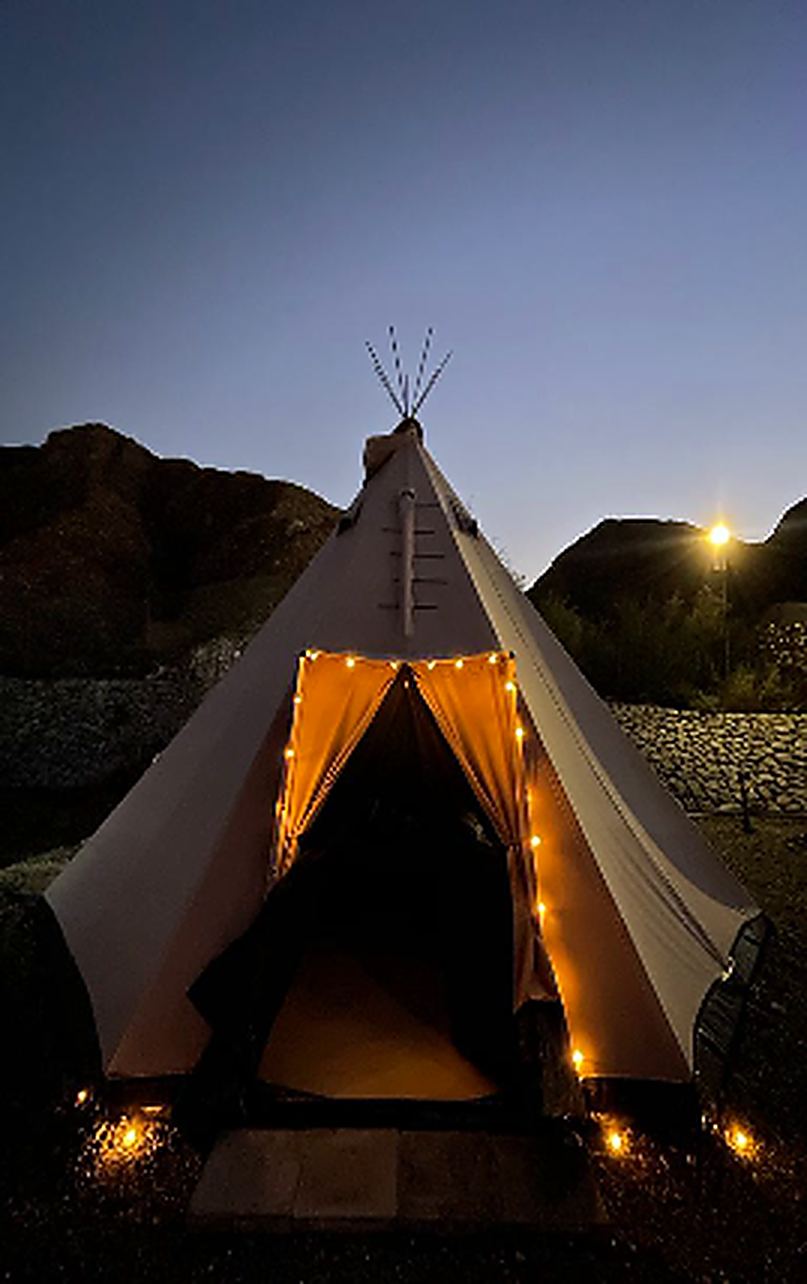 A teepee glowing from within at night under the stars